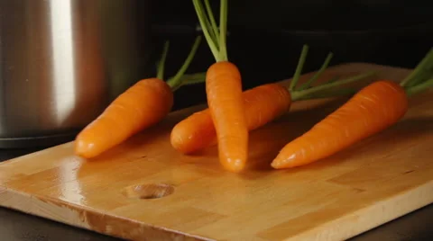 SLOW MOTION: Clean carrots fall on a cutting board on a kitchen Video stock 68155810