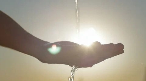 Slow motion of clean water falling on a human hand against the sun Stock Footage 67042677