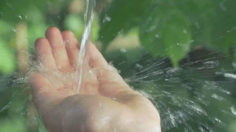 Slow motion of clean water splashing on a human hand in nature 動画素材 74632655