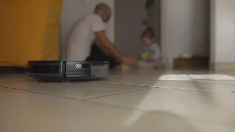 Slow motion: Cleaning robot does housework meanwhile father plays with his child Stock Footage 143650343