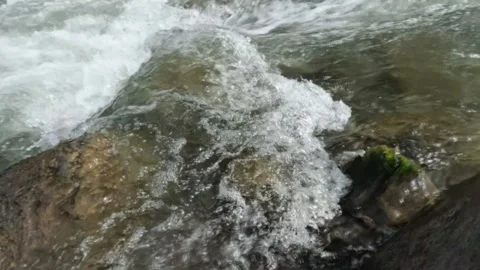 Slow motion of a clear flowing mountain river in the rocks of the river Video stock 320984799