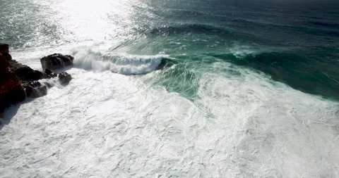 Slow motion of clear ocean water washing over big boulders close to rocky cliffs Stock Footage 156097170
