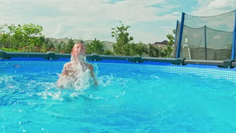 Slow motion clip: Happy boy having fun in the private pool.  White boy jumps  Stock Footage 166182036