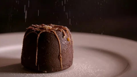 Slow motion clip of icing sugar being sprinkled on a chocolate dessert Stock Footage 87857583