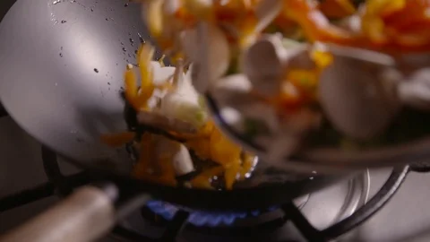 Slow motion clip of sliced vegetables being poured into a wok ready for fryin Stock Footage 87857617