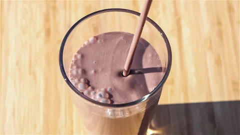 Slow motion clip of thick chocolate milk pouring into a clear drinking glass Stock Footage 148400628