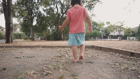 Slow Motion clip of a two year old Asian boy walking barefoot on the sand Stock Footage 124448846