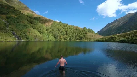 SLOW MOTION, CLOSE UP: Active male tourist jumps head first into the refreshing Video stock 121860037
