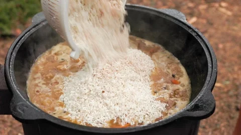 Slow motion close-up of adding rice to cauldron with meat and vegetables du.. Stock Footage 319660593