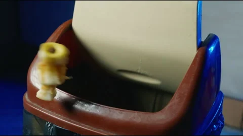 Slow Motion Close-Up: Apple Core Missing Kitchen Trash Bin and Bouncing Off Lid Stock Footage 326848499