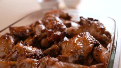 Slow-motion close-up of baked chicken pieces in a glass mold on the table. Stock Footage 250394247