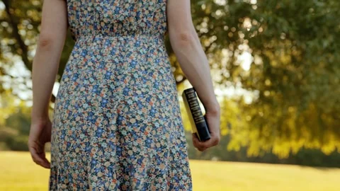 Slow motion close-up of Bible in womans hand as she walks through golden meadow Stock Footage 310439081