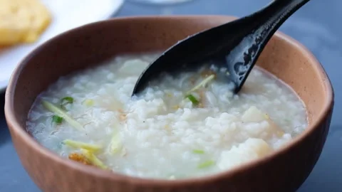 Slow motion close up of black spoon scooping hot rice porridge with ginger .. Stock Footage 333943591