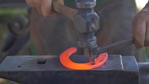 Slow motion close-up of blacksmith making holes on red hot horseshoe Stock Footage 255837490