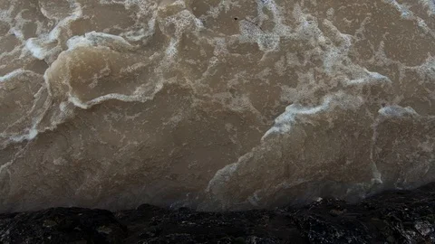 Slow motion close up brown chaotic river flowing against concrete wall Stock Footage 120749083