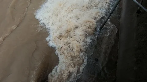 Slow motion close up brown dirty water flowing in concrete man made canal Stock Footage 122036525