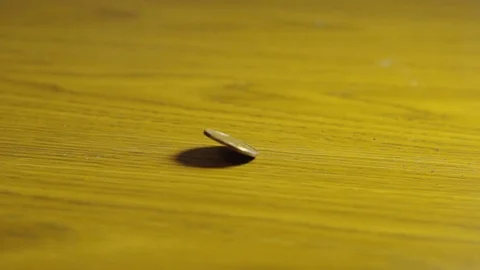 Slow Motion Close Up Canadian Loonie Coin Spinning And Stopping On Wooden Stock Footage 106987529