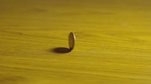Slow Motion Close Up Canadian Loonie Coin Spinning Circles On Wooden Table Stock Footage 106987586