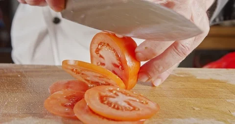 Slow motion close up of a chef knife slicing a tomato Video stock 125527801