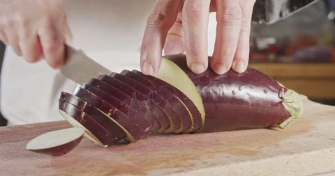 Slow motion close up of a chef knife slicing an Eggplant Stock Footage 125531776
