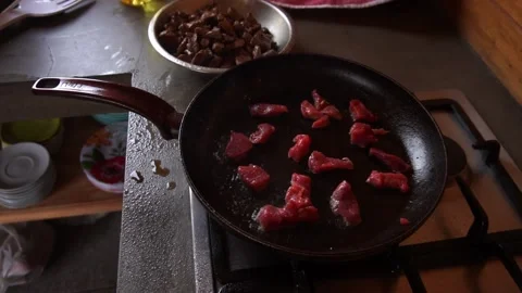 Slow motion close-up cooking small pieces of red meat in the pan splashing oil a 库存影片 199636179