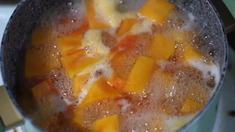 Slow motion close-up of diced ripe pumpkin boiling in a pot for making porridge Stock Footage 320359481