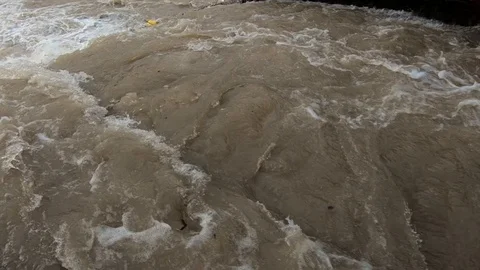 Slow motion close up dirty rainfall water flows in small concrete channel Video stock 120354142