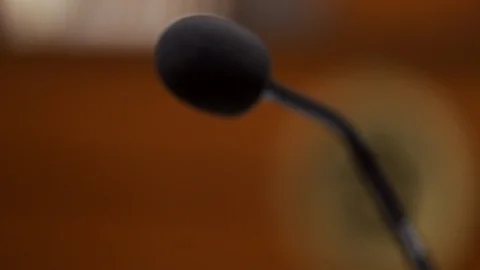 Slow motion close-up dolly shot of microphone on witness stand  Stock Footage 85576157