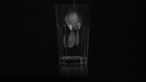 Slow motion close-up of falling ice cubes dropping into an empty clear glass Stock Footage 315062374