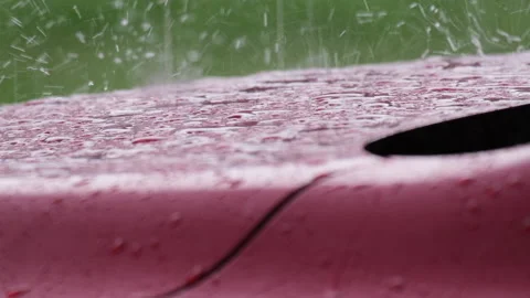 Slow motion close-up of falling rain and the bouncing raindrops on red car hood. Stock Footage 188491974