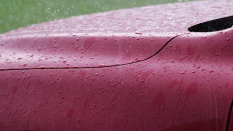 Slow motion close-up of falling rain and the bouncing raindrops on red car hood. Stock Footage 188492278