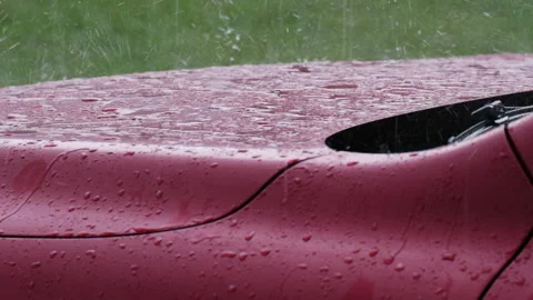 Slow motion close-up of falling rain and the bouncing raindrops on red car hood. Stock Footage 188492479