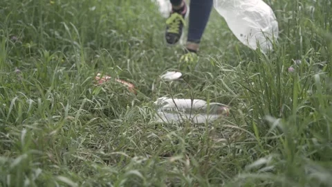 Slow motion close-up of feet walking on the grass, on which there is garbage Stock Footage 242091206