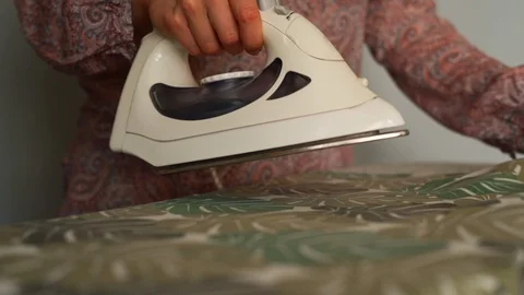 Slow Motion Close up on Floral Pattern Cloth Ironed on Wobbly Ironing Board Stock Footage 106012273