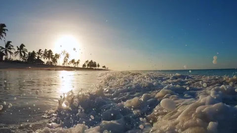 Slow motion close-up of the foaming spray wave on the beach with silhouettes of Stock Footage 243572711