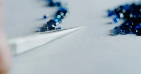 Slow motion close up of goldsmith sorting high quality fuxia diamonds. Video stock 114942557