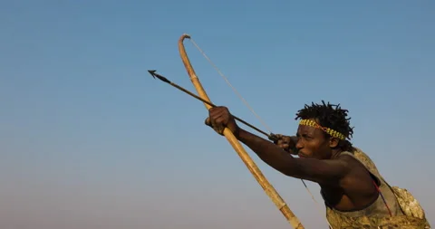 Slow motion close-up Hadza hunter-gatherer tribesman aiming to shoot bow arrow Video stock 160909345