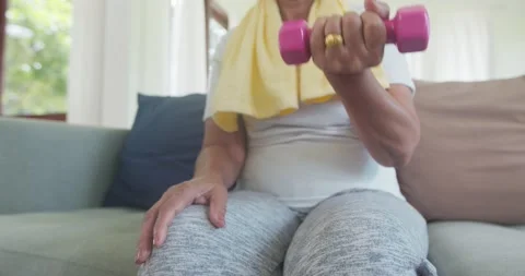 Slow motion of close up hand of old woman exercise by dumbbell on sofa at home Stock Footage 138515785