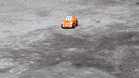 Slow-motion close-up: hand pushing a toy race car on an outdoor concrete floor. Stock Footage 320588049