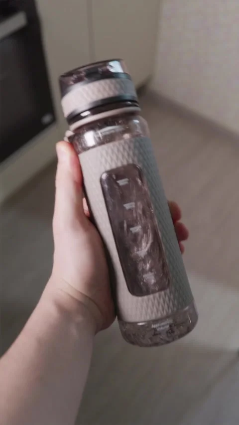 Slow motion close up of hand shaking transparent sports water bottle Video stock 344877793