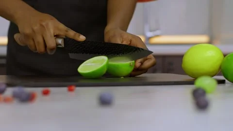 In a slow-motion close-up, hands holding a huge sharp knife cut a green juicy Stock Footage 269893780