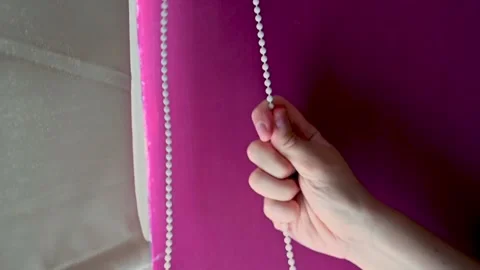 SLOW MOTION CLOSE UP of hands pulling open a roller blind Stock Footage 148338981