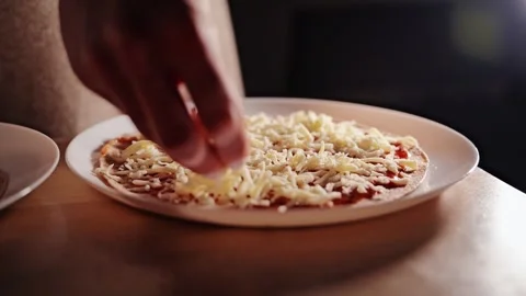 Slow Motion Close Up Of Hands Sprinkling Grated Cheese Over Homemade Pizza Base. Stock Footage 348766975