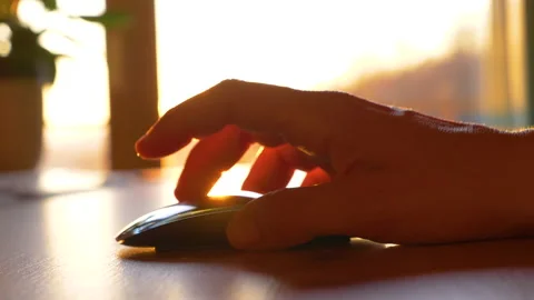 SLOW MOTION, CLOSE UP: Human hand clicking on wireless computer mouse at sunrise Stock Footage 191748671