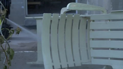 Slow motion close up jet spray gun spraying white wooden chair laying on grou Stock Footage 157007611