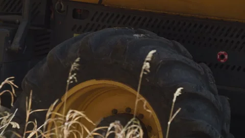 Slow motion close up of large tractor tire through tall dry brown grass Video stock 327569780