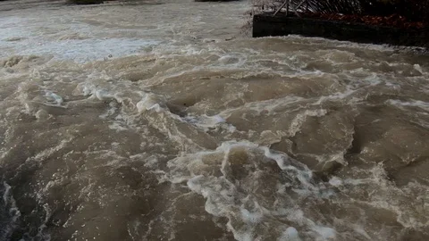 Slow motion close up left pan spillway canal with flooded brown water Stock Footage 120391171