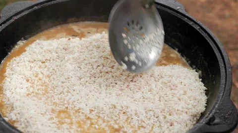 Slow motion close-up of leveling rice layer in cauldron during traditional .. Stock Footage 319660682