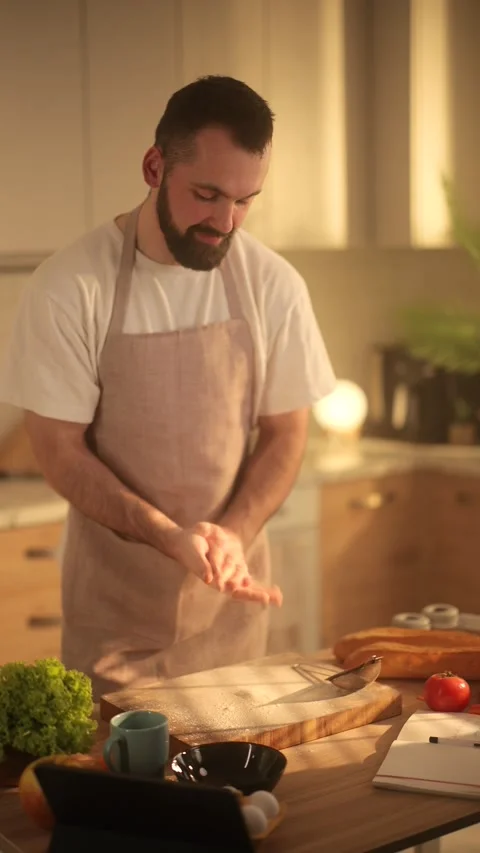A slow-motion close-up of a man in an apron shaking flour off his hands while Stock Footage 304611103