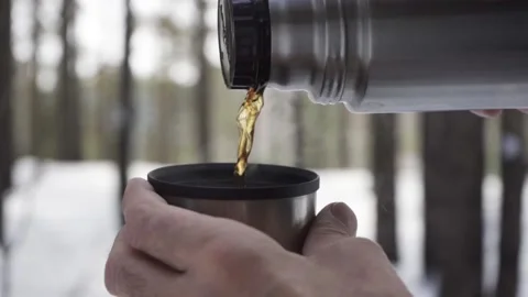 Slow motion: Close-up of a man pouring hot tea from a thermos into a mug Stock Footage 171907819